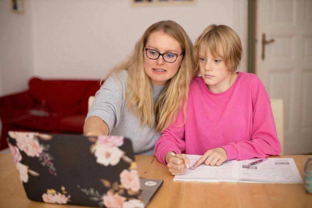 A mother and child engaged in study at a desk with a laptop, fostering education.