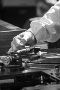 Close-up of DJ adjusting turntable during a live music event, showcasing classic retro vibe.